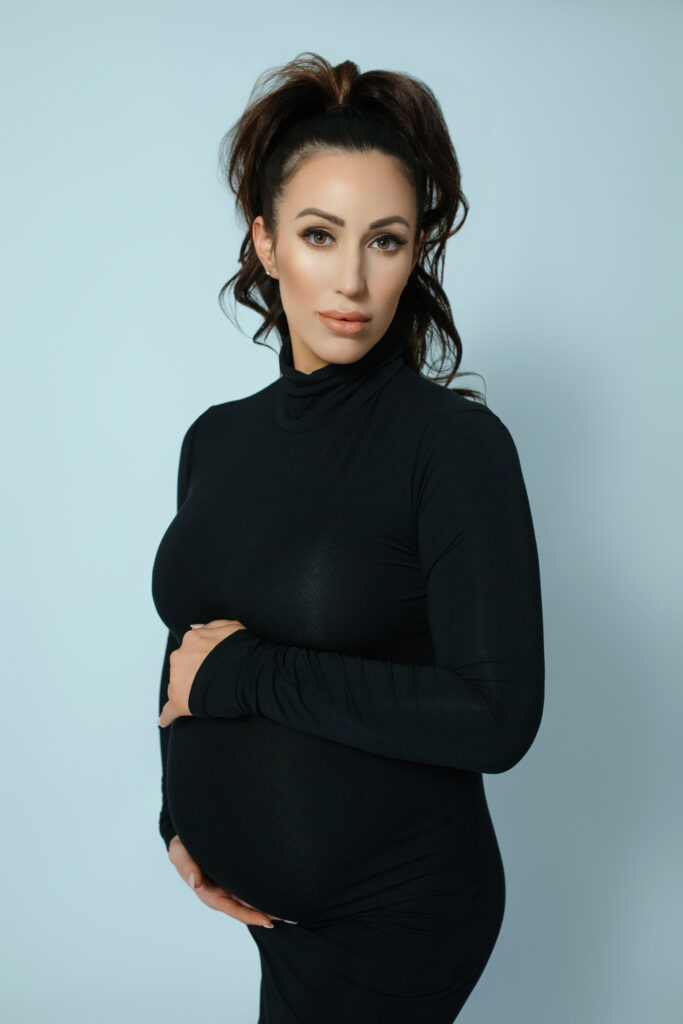 Vogue-inspired maternity photography in Oklahoma City with black dress, pale blue backdrop, and modern look