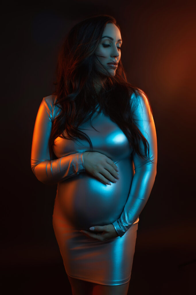 Editorial maternity photography in Oklahoma City featuring silver metallic mini dress with dramatic gel lighting
