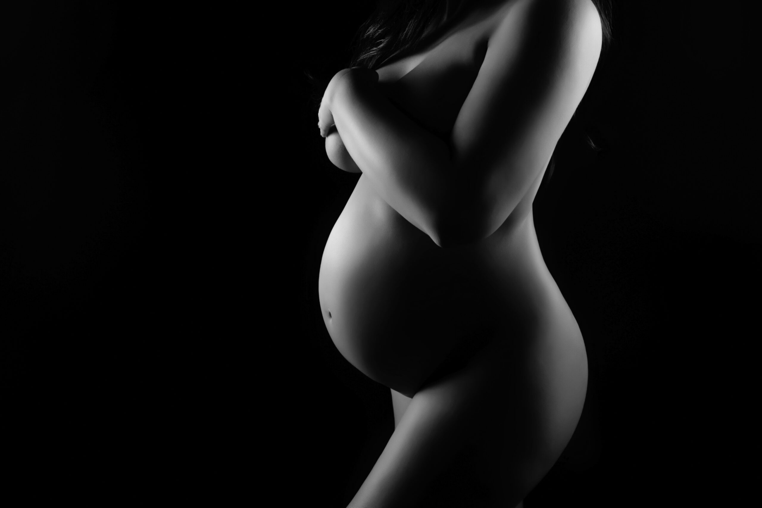 Black and white editorial maternity bodyscape in Oklahoma City highlighting the baby bump with artistic lighting