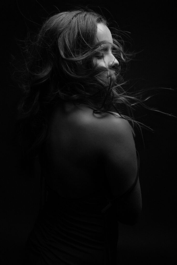 Emotional black and white studio portrait of woman with dramatic wind-swept hair